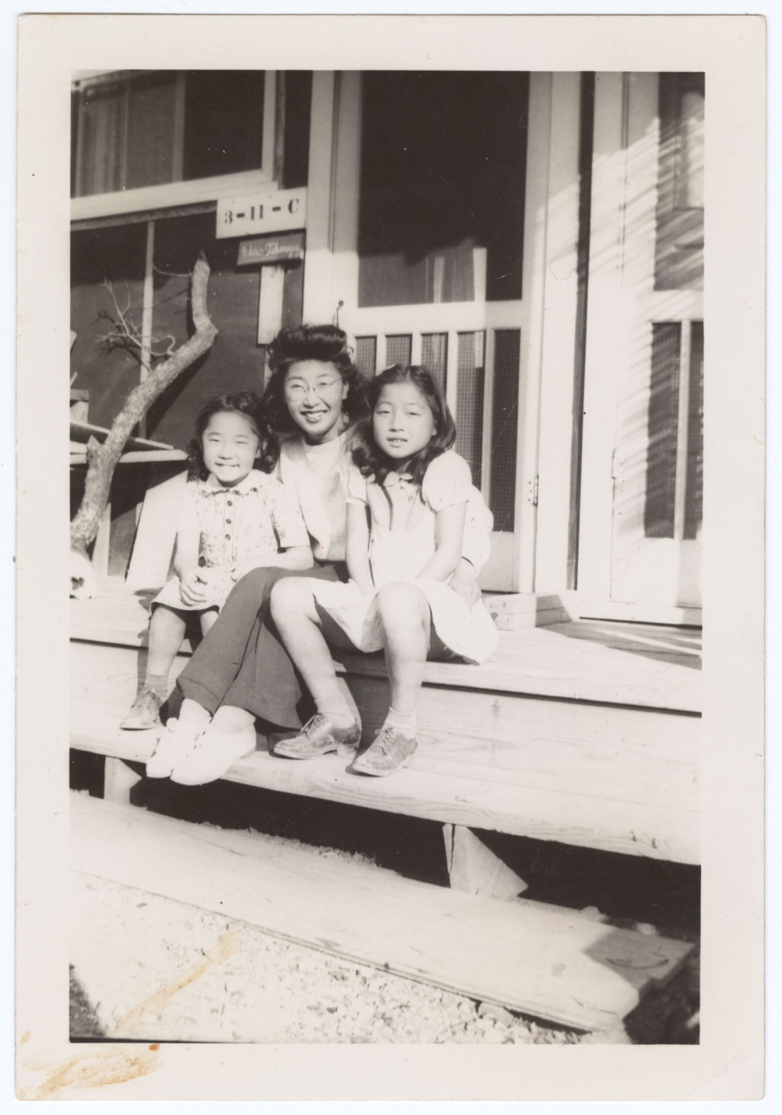 Yuri sitting on a porch with two young girls
